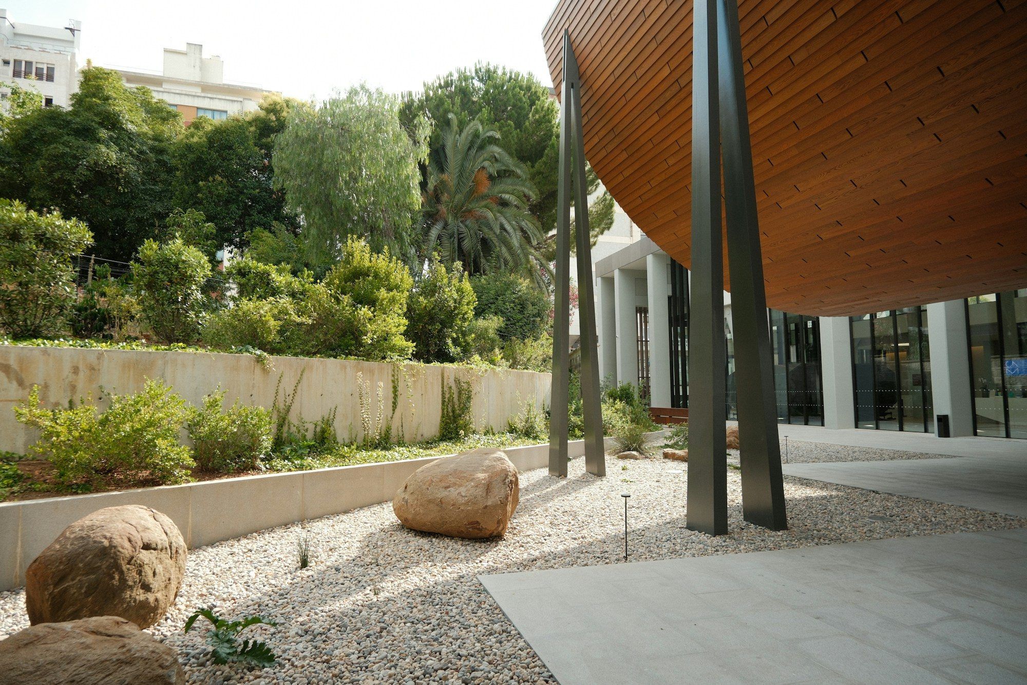 Jardin contemporain en graviers et rochers devant une maison à façade en bois