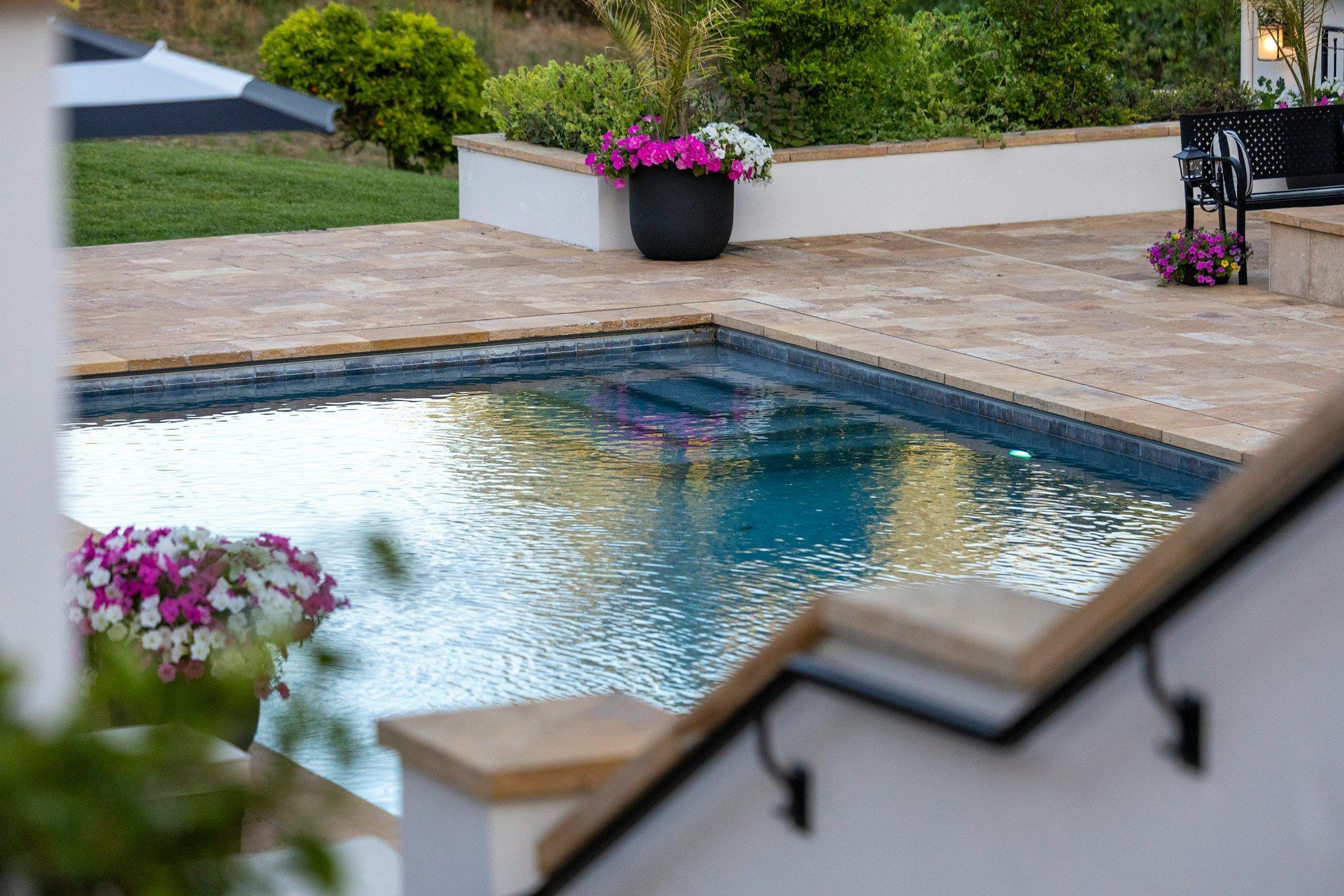 Piscine entourée d’une plage en pierre et de massifs fleuris